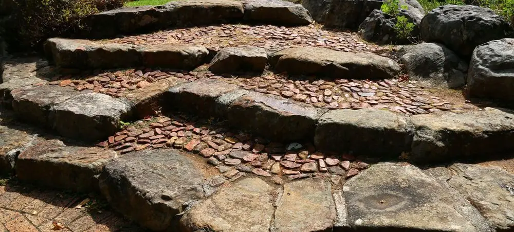 Flache Steinstufen mit Mosaik aus kleinen Steinen in einem Garten